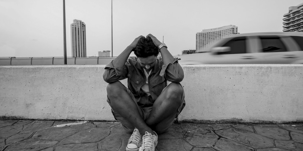 man sits on the ground in despair black and white photo
