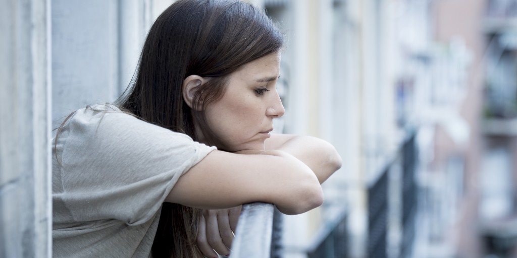 woman leaning on balcony struggling with substance abuse