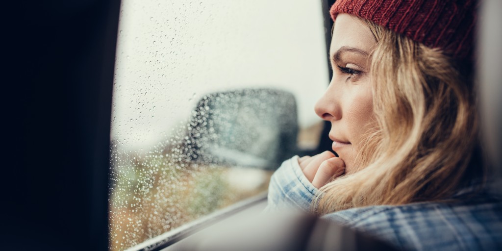 woman looking out a rainsoaked car window as she sits in traffic