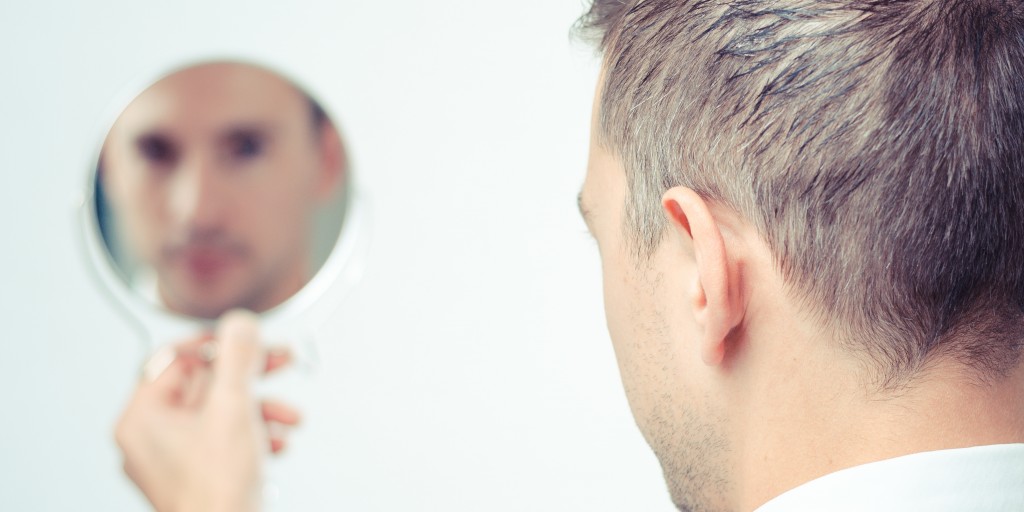 man looking at himself in a small circular mirror