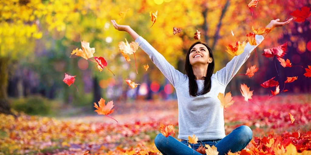 woman sitting crosslegged on the ground enjoying the pretty autumn leaves